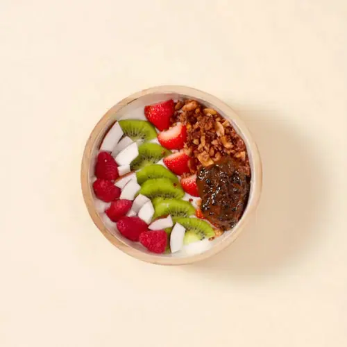 Coconut granola bowl with strawberries, raspberries, kiwi, and coconut flakes