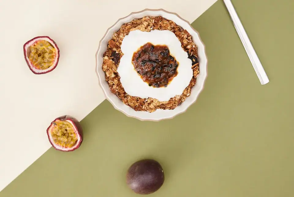 Granola with yogurt and passion fruit spread, with fresh passion fruit alongside