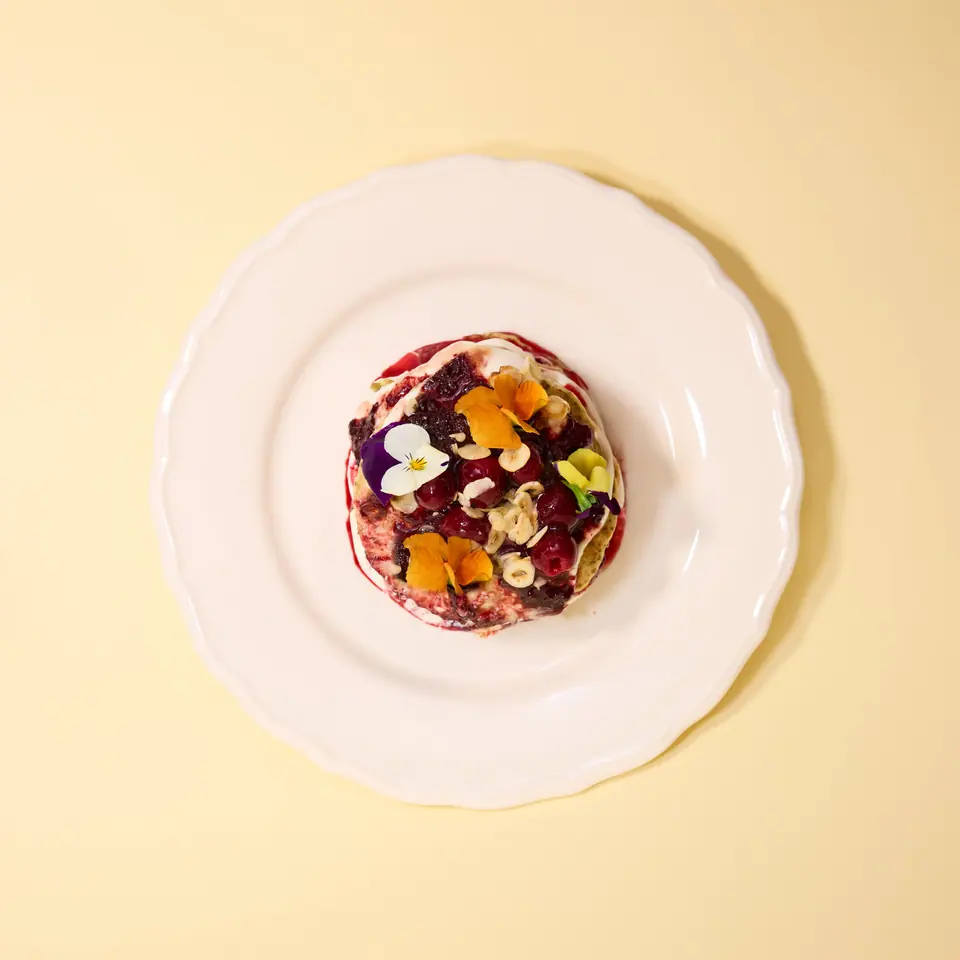 Chia pancakes topped with cherry and rhubarb spread, nuts, and herbs