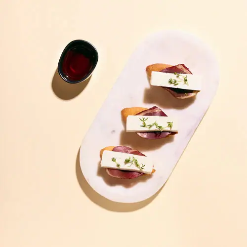 Cherry salsa and goat cheese crostini arranged on a pink serving platter
