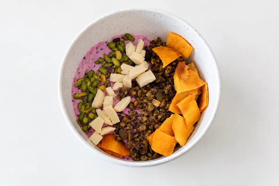 Dragon fruit and matcha granola bowl with sliced fruit and coconut flakes
