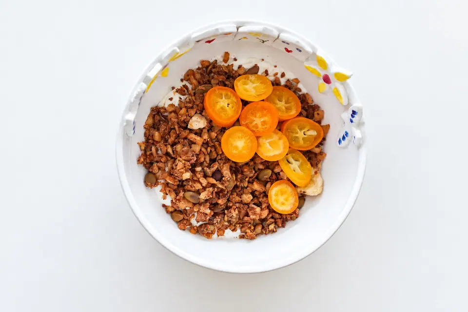 Dried fruit granola topped with sliced kumquats in a bowl