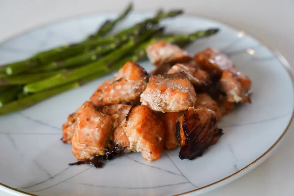 Fig balsamic salmon pieces served with asparagus on a white plate