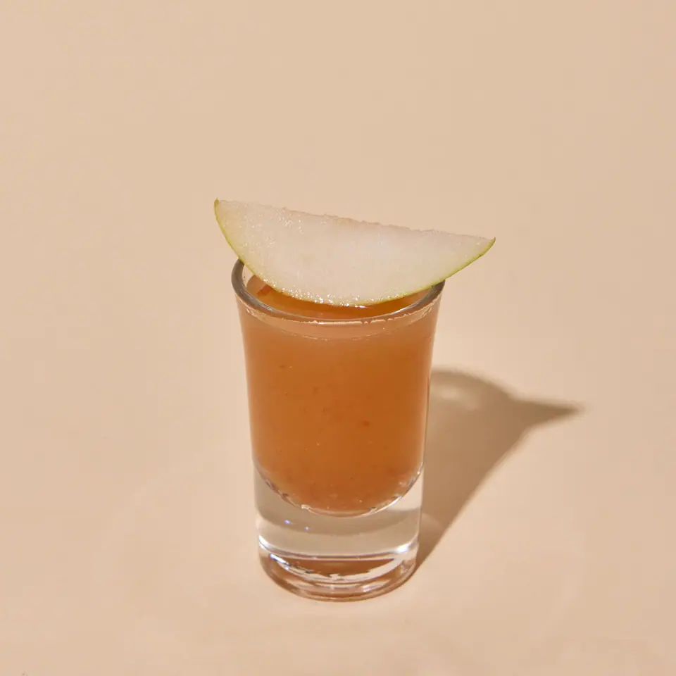 Ginger-spiced pear citrus shot garnished with a thin pear slice