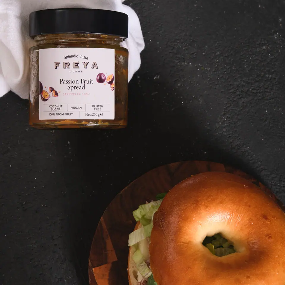 Passion fruit tuna sandwich in a round bread roll beside a Freya spread jar