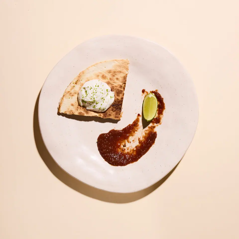 Strawberry jalapeño quesadilla with a dollop of cream and a wedge of lime